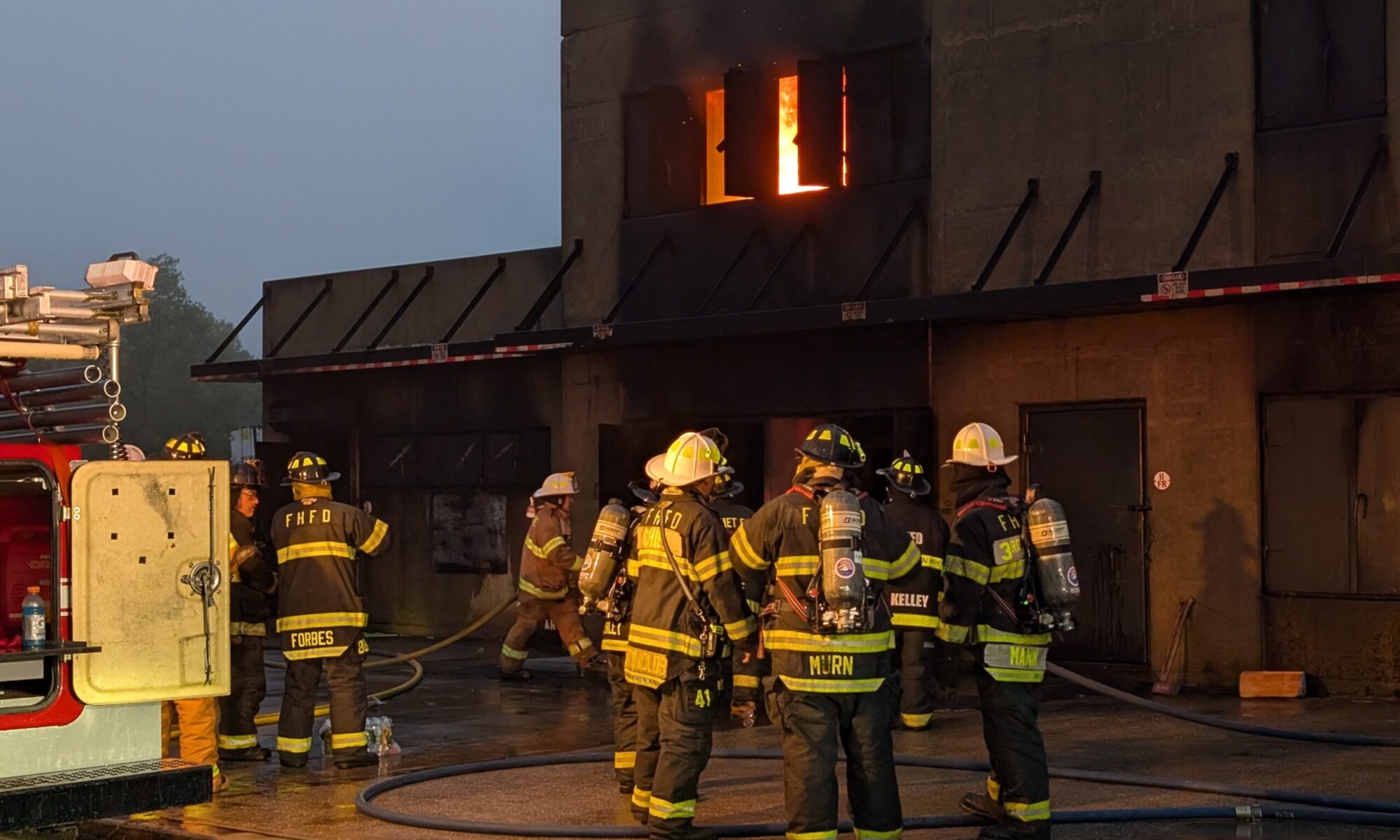 FHFD Firefighters train at the Suffolk County Fire Academy, with live fire shown on the second floor of a concrete building
